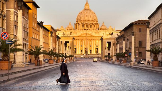 A nun looks both ways in front of St Peter’s Basilica, in Rome